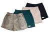 Front view of four pairs of Go Wild Boxers, one Black, one Tan, one Green, and one Leopard Print. Each have an elastic waistband, a buttoned front fly, and a Tag Buffalo label on the bottom front of the left leg. 100% cotton.