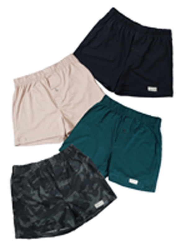 Front view of four pairs of Go Wild Boxers, one Black, one Tan, one Green, and one Gray Camouflage. Each have an elastic waistband, a buttoned front fly, and a Tag Buffalo label on the bottom front of the left leg. 100% cotton.