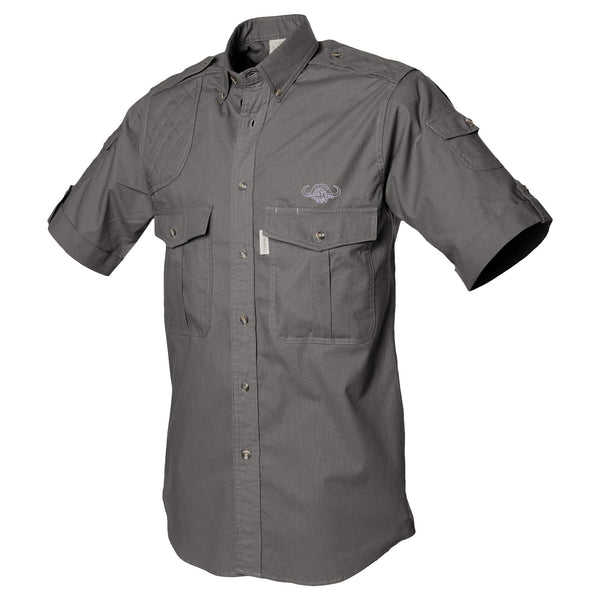 Side view of a Men's Shooter Shirt with Buffalo Logo in Short Sleeves, color Olive. The shirt has a quilted shooting pad at the right shoulder, ammo pockets on the sleeves, two flap-covered chest pockets with an embroidered Tag buffalo logo above the left pocket, button-down collars, functional cross-stitched shoulder straps, a button-front placket, double stitching throughout, and long rounded tails for tucking into pants. 100% cotton.